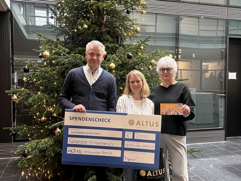 Der Geschäftsführer und eine Mitarbeiterin überreichen einen Spendencheck in Höhe von 2.500€ an den Karlsruher Kindertisch e.V.