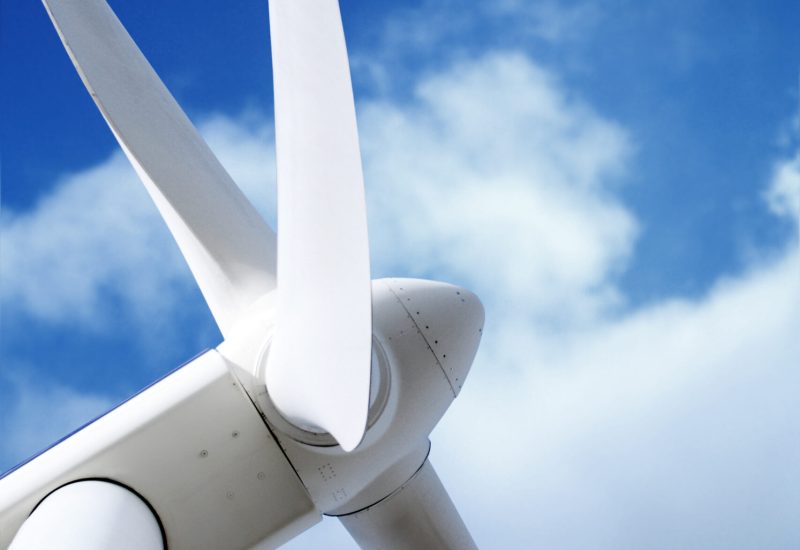 Ausschnitt einer Windenergieanlage inklusive Gondel und Rotorblätter.